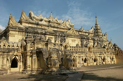 Front view of the Maha Aung Mye Bonzon Monastery, a brick building adorned with intricate stuccoed sculptures