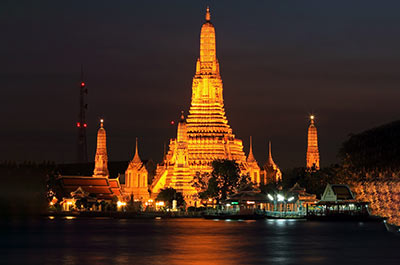 The illuminated Wat Arun, also known as the temple of Dawn, standing on the banks of the Chao Phraya river