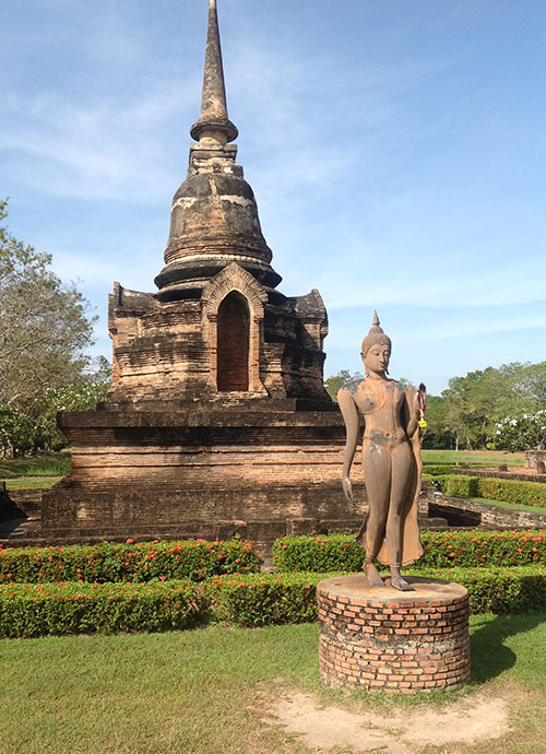 A chedi and a Sukhothai style walking Buddha