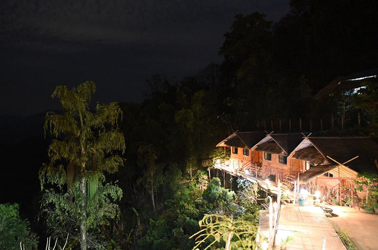 Akha mud houses at night overlooking the forest