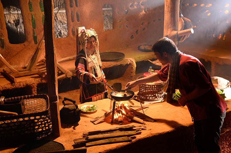 Akha hill tribe woman cooking food in a mud house