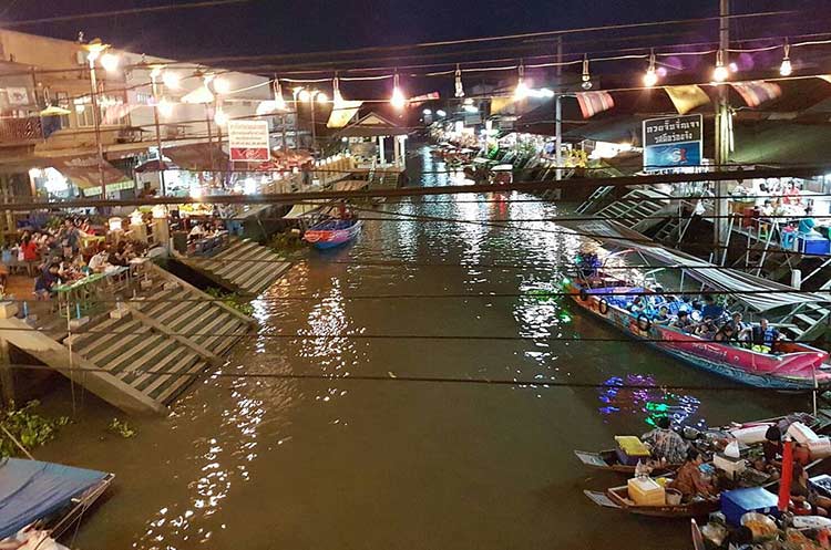 Amphawa floating market with boats on the canal and restaurants along the water