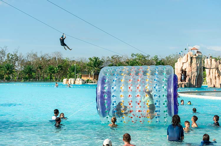 Children in a zorb ball on the lagoon and zipline over the Blue Tree Lagoon