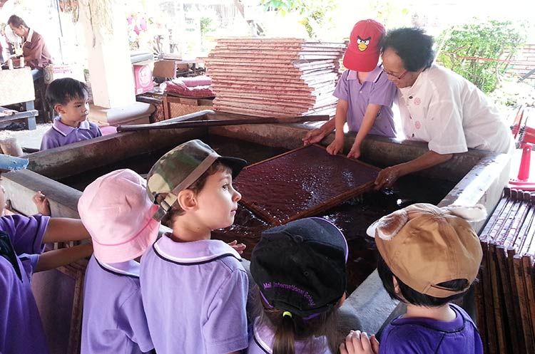Children watching how paper for umbrellas is made at Bo Sang umbrella village