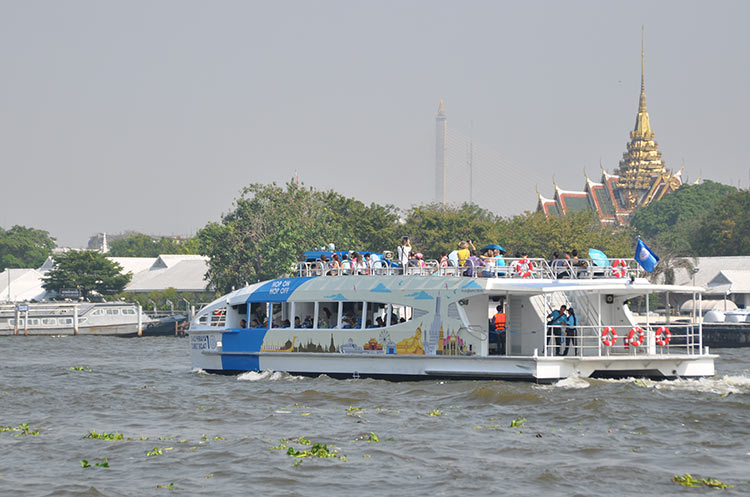 A Chao Phraya tourist boat on the river floating past the Grand Palace