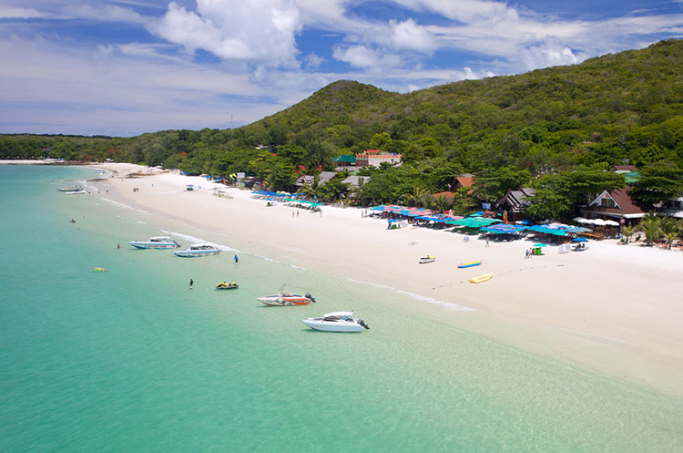 Sandy beach, forested mountains and clear sea at Coral Island, Koh Larn