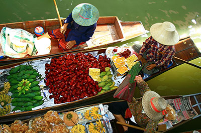 Women offering fresh fruits and vegetables on their boats at Damnoen Saduak floating market