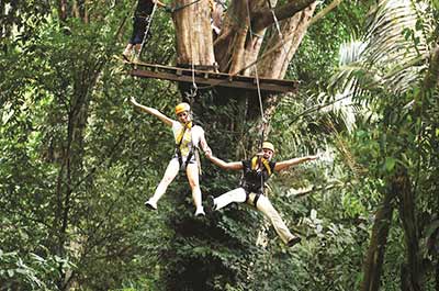 Two people ziplining in the tropical rainforest in Phuket