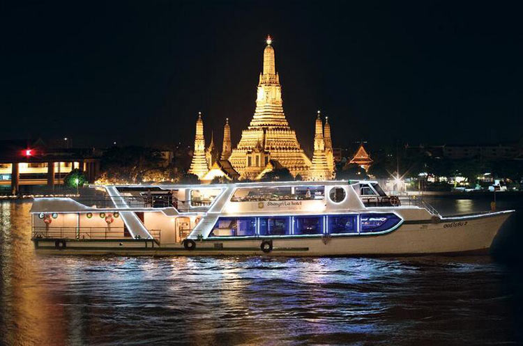 The Horizon Dinner Cruise ship floating past the illuminated Wat Arun on the Chao Phraya river in Bangkok