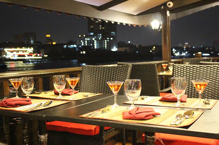 Dining table aboard the dinner cruise barge overlooking the Chao Phraya river