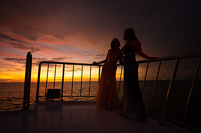 Two women on deck of the Melody cruise ship while the sun sets in the Andaman Sea