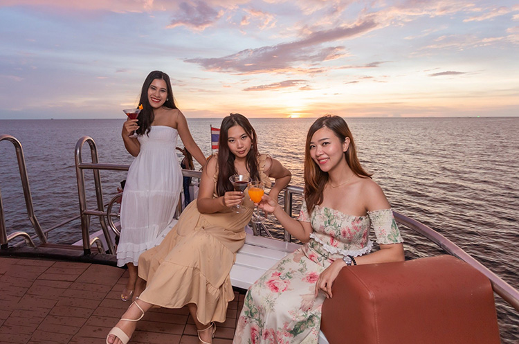 Three women on deck of the ship sailing towards the sunset