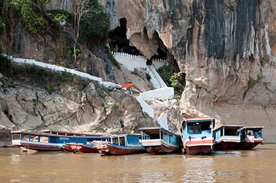 Boats on the Mekong river moored at the entrance to the Pak Ou Caves