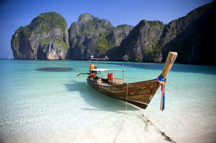 A longtail boat on a white sandy beach in Thailand