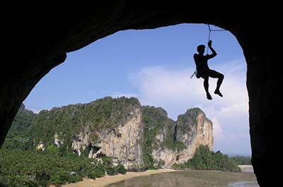 A climber hanging down from a rope on the limestone mountains of Krabi