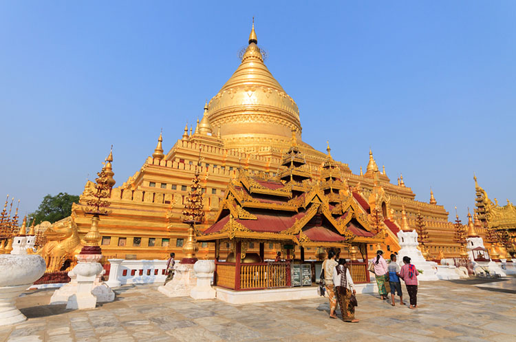 People walking past a tazaung, a Burmese style open pavilion