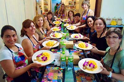 Students holding a plate with sticky rice with mango at Silom Thai cooking school