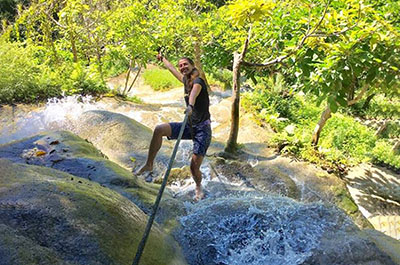 Someone climbing the rocks of the Sticky Waterfalls