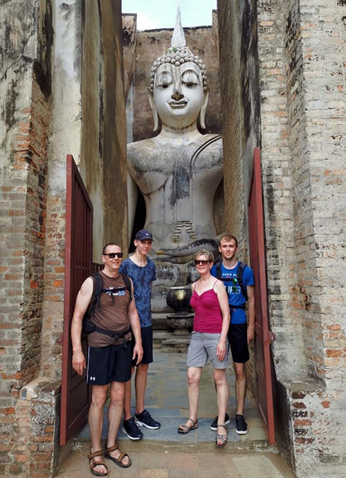 Cyclists at a huge Buddha image in Sukhothai Historical Park
