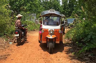 A tuk tuk driving on a rural dirt road in North Thailand