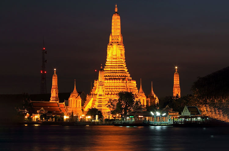 The illuminated central prang of the Wat Arun temple on the banks of the Chao Phraya river