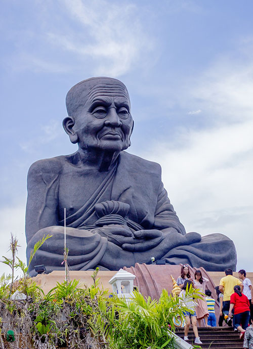 People climbing the stairs to the statue of the famous monk Luang Phor Thuad