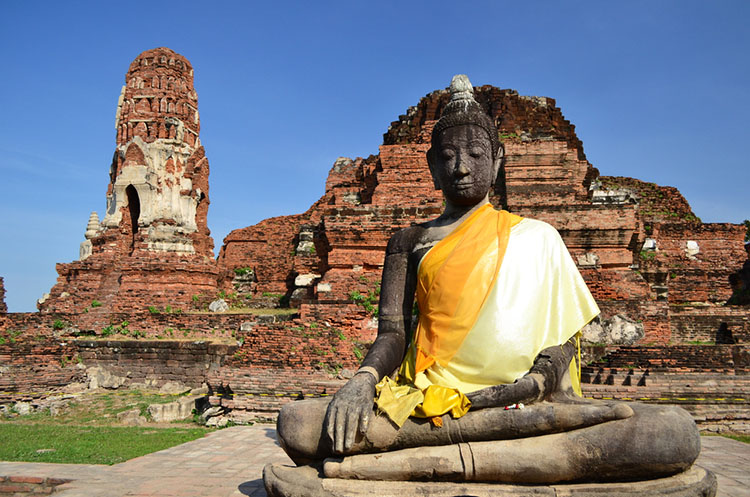 Buddha image in front of the ruins of a chedi at Wat Mahathat